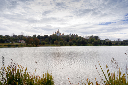 The church is located among the trees. In front of it is a lake. Landscape.