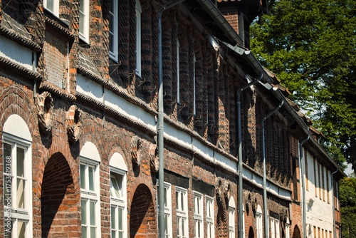 Obraz na plátně Weathered historic brick facade with arched windows and ornate timber beams in a quaint European town on a sunny day