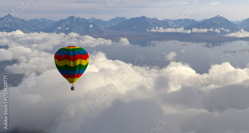 Colorful Rainbow Hot Air Balloon Floating Above Clouds Over Distant Mountain Range