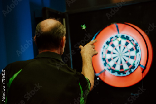 Man playing darts, aiming at an electronic dartboard during a game. Concept of precision, focus, leisure activity, and competitive sport.