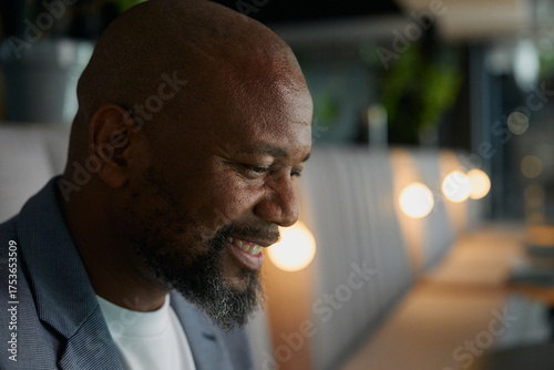 Closeup side view of bald mature businessman smiling while deep in thought in office