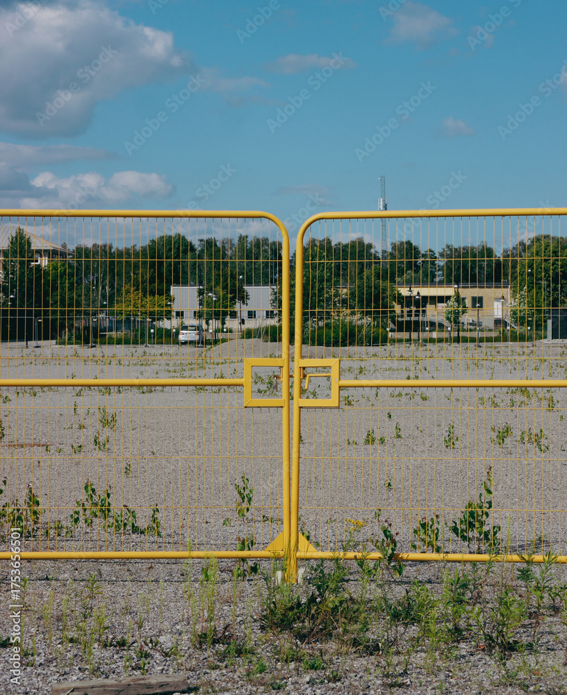 Fototapeta premium Yellow metal gate in front of empty field