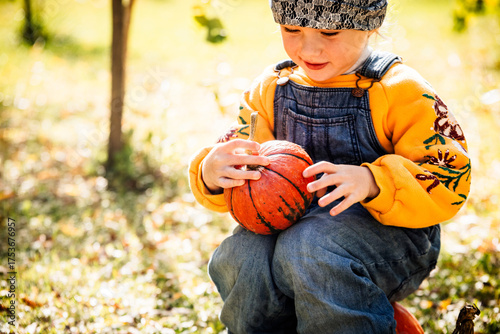 Happy child wearing warm clothes and holding pumpkin