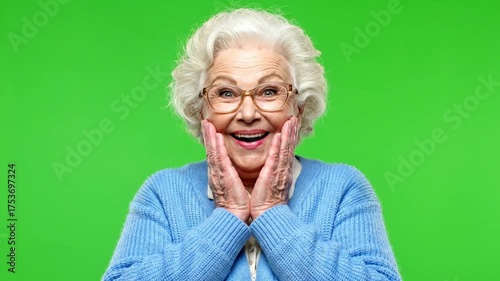 Excited senior woman with glasses smiling happily on green screen.