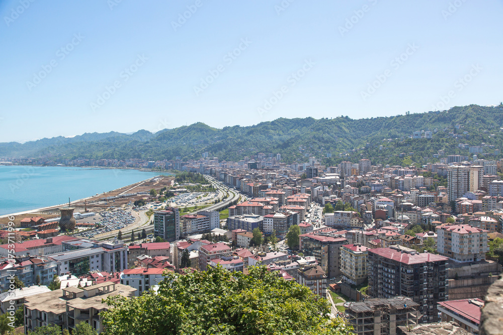 Obraz premium Panoramic view of Rize city on the Black Sea coast, Turkey, with modern buildings, green mountains, and blue sky, perfect for travel, tourism, and urban landscape concepts