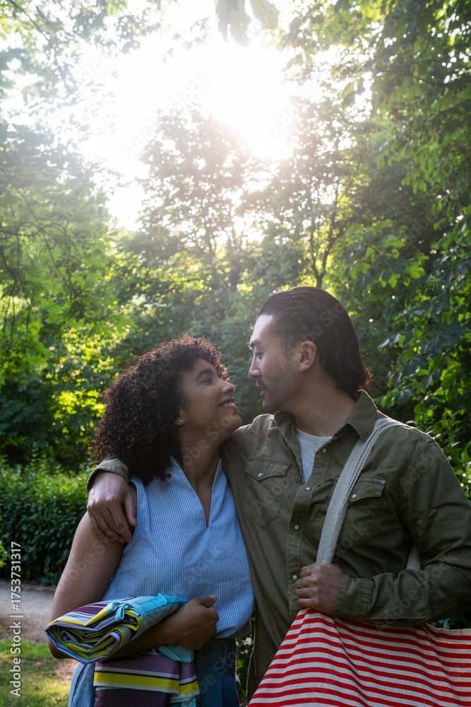 Fototapeta premium Interracial couple walking arm in arm enjoying park