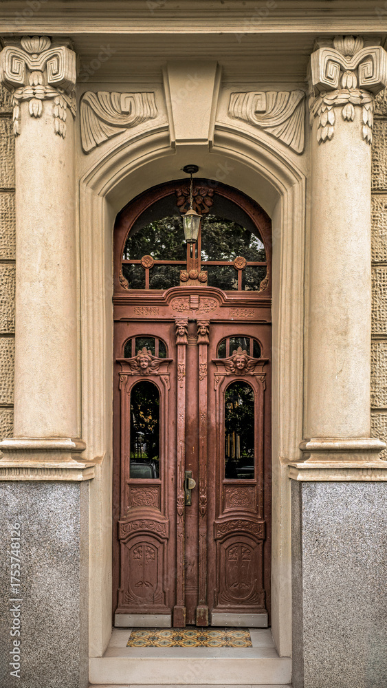 Obraz premium ornate wooden double door framed by stone columns and classical architectural details, front view of historic european building entrance