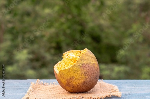 Closeup of Ripe Indian Bael Fruit Juice or Wood Apple Isolated on Wooden Background with Copy Space, Also Known as Aegle Marmelos, Bengal Quince, Japanese Bitter Orange