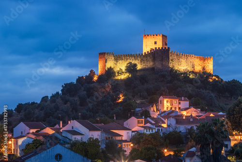 Belver, Portugal at dusk with the castle illuminated on top of the hill.
