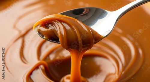 A silver spoon lifting thick dulce de leche dripping slowly