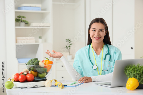 Portrait of female nutritionist with vegetables at table in office