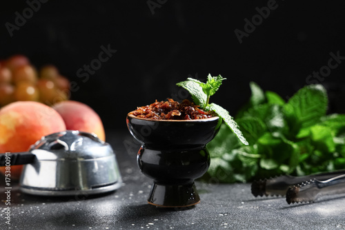 Obraz na plátně Hookah bowl of tobacco with fruits and mint leaves on black background