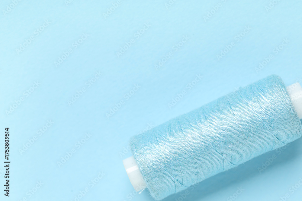 Obraz premium Spool of thread on blue background