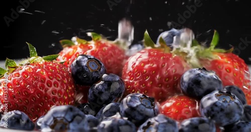 Fresh strawberries and blueberries splashing in water
