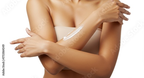 Against a clean backdrop, young woman carefully applies moisturizer to her forearm, emphasizing the importance of daily skincare and self-care rituals.