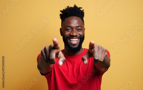 Young african american man with beard wearing casual red t shirt pointing fingers to camera with happy and funny face. good energy and vibes. High quality