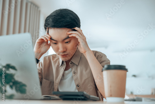 Asian man are stressed, pain in their eyes, working on laptop in living room at home