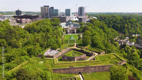 old historical site city walls green cover central fountain district center visible distance luxembourg to left right panning shot aerial view urban landscape 
