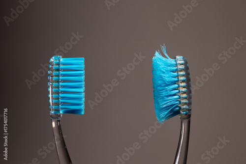 A new toothbrush with firm bristles stands next to an old, worn toothbrush. This comparison illustrates the importance of regular toothbrush replacement for optimal dental health.