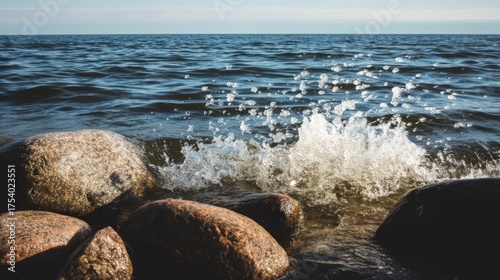 Sunny beach seascape with waves crashing over large rocks,