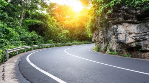 A winding asphalt road bordered by greenery, metal guardrails lining the path,
