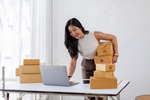 Fotografie Asian female sme small business entrepreneurs are working in the stock room, preparing their shipping sme boxes to sent to a postal delivery service