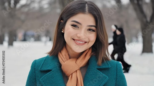 A smiling young woman enjoying a winter day outdoors wearing a coat and scarf