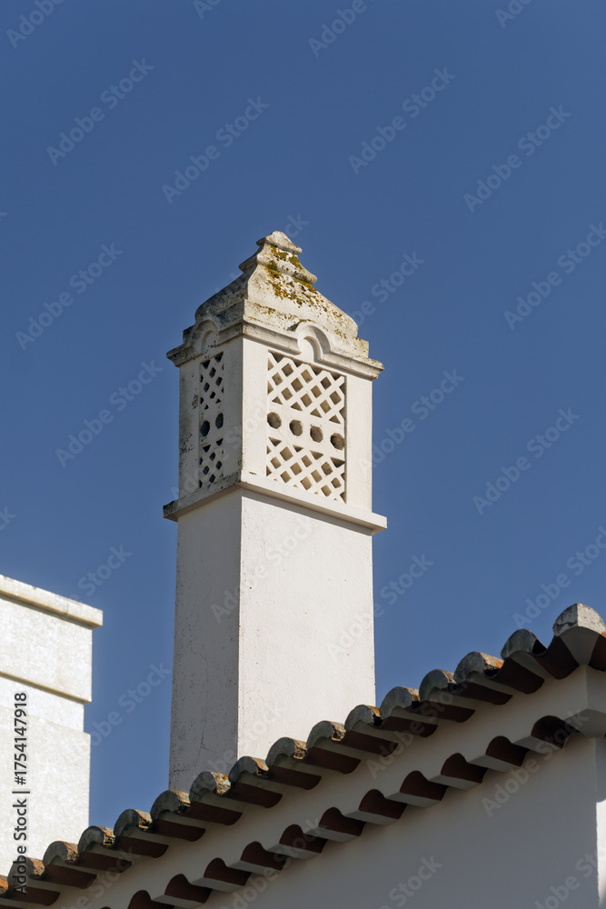 Fototapeta premium Ornate chimney with decorative top structure Terracotta roof tiles below in Portimao, algarve, Portugal