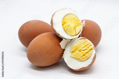 a boiled egg is cut in half, showing the texture of the white and yolk against the background of other whole eggs on a white background