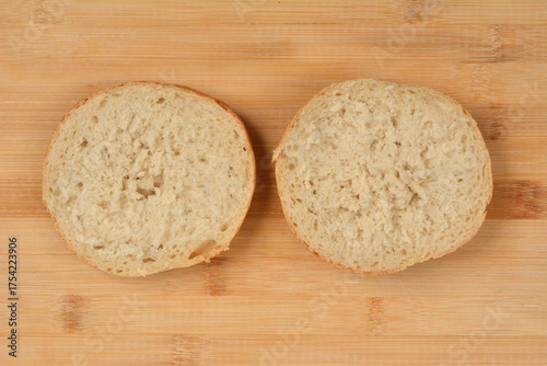 Fotografia Two halves of a rustic bread roll are placed side-by-side, cut-side up, on a lig