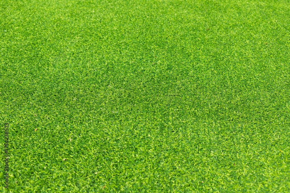 Fototapeta premium Close-up of lush green artificial grass, showcasing its detailed texture and vibrant color, perfect for outdoor landscaping and sports fields.