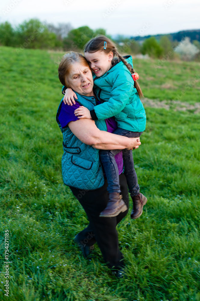 Fototapeta premium Grandmother and granddaughter sharing a joyful moment outdoors.