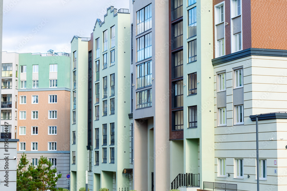 Fototapeta premium A modern residential complex with vibrant pastel-colored facades, large windows, and landscaped grounds. Buildings of varying heights create a cozy urban landscape.