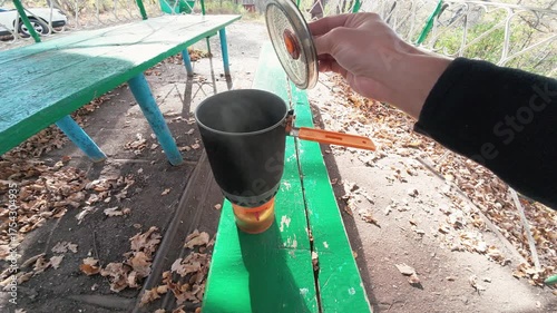 A series of images highlights a portable stove in a scenic park. A skilled cook prepares a meal, enjoying nature while demonstrating outdoor cooking techniques with ease and flair