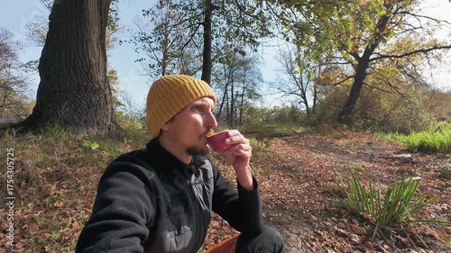 By the calm waters edge, a person sips a warm drink beside a paddle board, surrounded by stunning autumn scenery, creating a peaceful atmosphere ideal for unwinding and rejuvenating the spirit