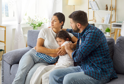 Family parents comfort child in crisis. Mother and father provide steady support and care on the sofa, easing stress and anxiety in a bright home interior. Parental support in family crisis.