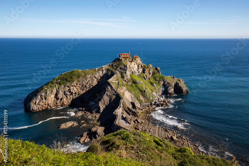 Stunning coastal hermitage atop rugged cliff with winding stone staircase leading to ancient structure overlooking azure ocean waves