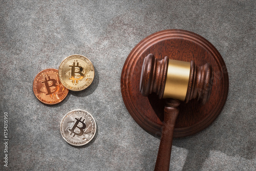 Photos A judge gavel with gold, silver and copper Bitcoin coins in on a gray stone surface with sunlight, representing cryptocurrency regulation and law