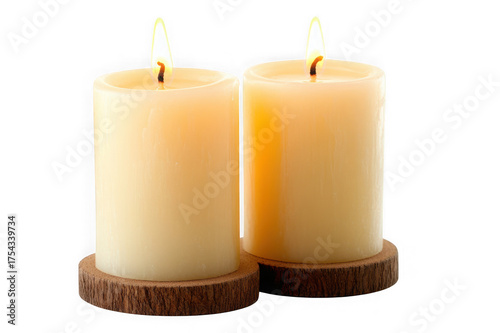 Two lit cream pillar candles on dark wood coasters against black background flame burning