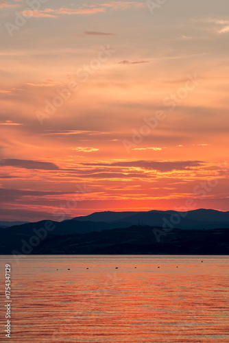 Golden sunset over a serene Aegean sea, with gentle waves and clouds illuminated by the warm evening glow.