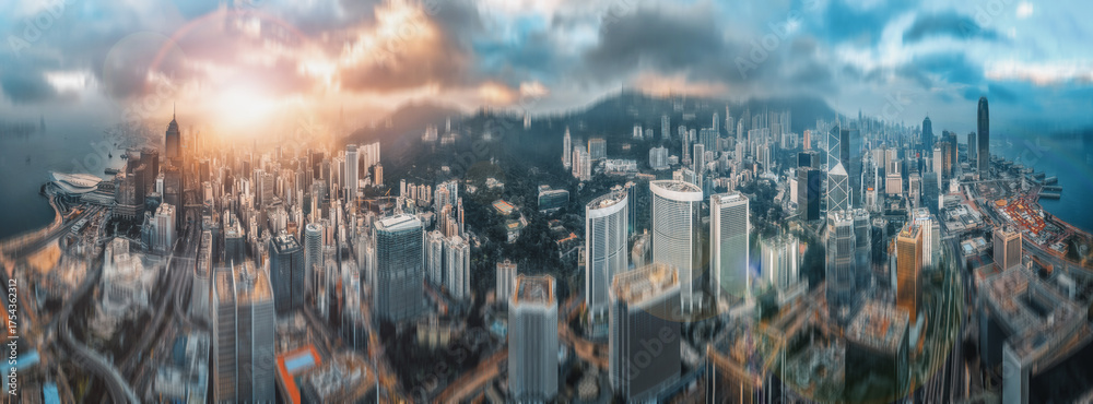 Fototapeta premium Panoramic double exposure showing a cityscape with a vibrant sky and high-rise buildings. The blurred effect and hazy light creates a dynamic, urban view.