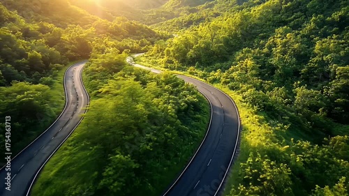 Winding Road Through Lush Green Landscape at Sunset Surrounded by Majestic Mountains