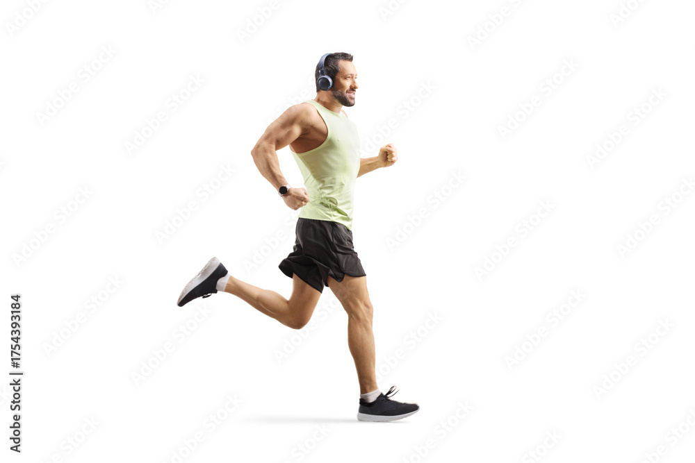 Fototapeta premium Full length profile shot of a man with headphones jogging