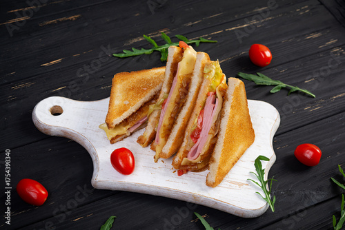 Club sandwich with ham, tomatoes, cheese and herbs. Toasts with filling