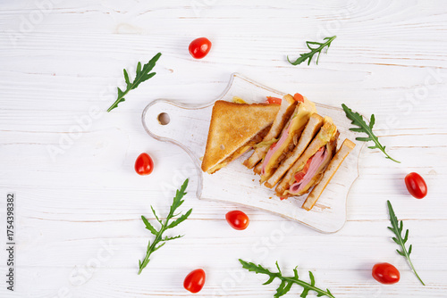 Club sandwich with ham, tomatoes, cheese and herbs. Toasts with filling