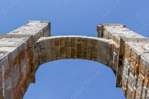 Low-angle view of a stone archway against a clear blue sky.