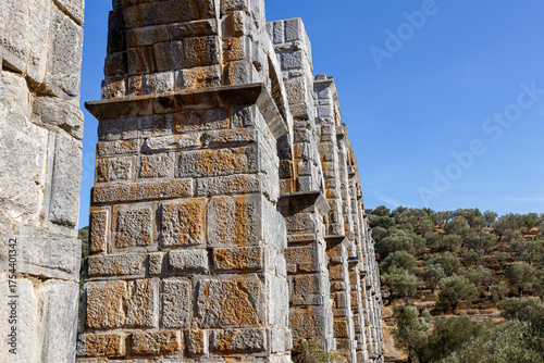 Ancient stone aqueduct with arches against a clear blue sky.