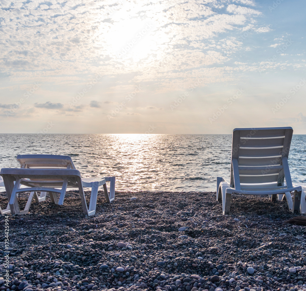 Fototapeta premium Set of white plastic patio chaise lounge at the beach. Outdoors