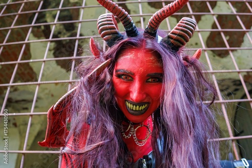 Demonic cosplay woman with horns and chains behind metal bars