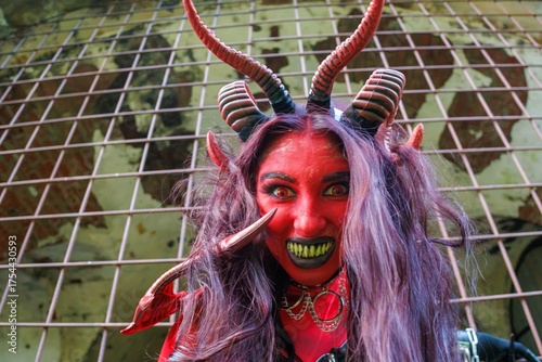 Demonic cosplay woman with horns and chains behind metal bars